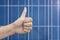 Thumb up on a solar panels background. Photovoltatic power industry.