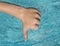 thumbs down sign of young man, teenager with blue water as background