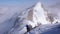 Thumbs up from a male backcountry skier hiking to a high alpine summit in Switzerland along a rock and snow ridge in light fog