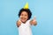 Thumbs up to birthday party! Excited amazing joyful little boy with funny cone on head showing like gesture