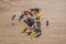 Thumbtacks of different bright colors are scattered randomly on a wooden background