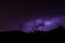 Thunderbolts over the mountains with purple sky