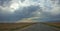 Thunderclouds are approaching the steppe, view from the road. Power line extending into the distance.