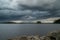 Thunderstorm with beautiful rainfall and dark clouds over a lake in sweden and rocks in the forground