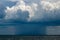 Thunderstorm on the horizon in the sea. Gray thunderclouds. In the distance, the size of the elements is clearly visible