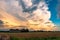 Thunderstorm with large anvil is colorfully lit during sunset