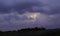 Thunderstorm with lightning in the middle of purple sky above dark trees in Minnesota