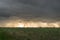 Thunderstorm with menacing clouds and rain streaks, backlit by the sun