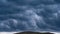 Thunderstorm over a hill on a hot summer day. Heavy leaden blue rain clouds low above the ground