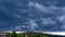 Thunderstorm over a hill on a hot summer day. Heavy leaden blue rain clouds low above the ground