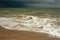 Thunderstorm over the ocean. A big waves is approaching an empty beach. Horizontal photo