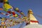 A Tibetan Buddhist Stupa Bodhnath with eyes and multicolored prayer flags against a clean blue sky at daytime