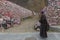 Tibetan monk walking in front of Mani stones wall with buddhist mantra Om Mani Padme Hum engraved in Tibetan in Yushu, China