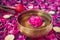 Tibetan singing bowl with floating inside in water purple peony flower. Burning candles, special sticks and petals on the black