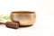 Tibetan singing bowl with mallet and cycad leaf on white background.