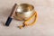 Tibetan singing bowl with stick, mala beads strands used during mantra meditations on beige stone background