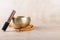 Tibetan singing bowl with stick, mala beads strands used during mantra meditations on beige stone background