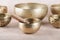 Tibetan singing bowls with sticks used during mantra meditations on beige stone background, close up