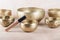 Tibetan singing bowls with sticks used during mantra meditations on beige stone background, close up