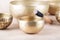 Tibetan singing bowls with sticks used during mantra meditations on beige stone background, close up