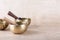 Tibetan singing bowls with sticks used during mantra meditations on beige stone background, copy space.