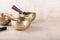 Tibetan singing bowls with sticks used during mantra meditations on beige stone background, copy space.