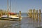 Tidal harbour with sailboats and mooring posts at low tide