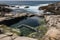 tidal pool surrounded by cliffside rocks, with view of the open ocean