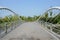 Tied arch bridge with asphalted roadway over water in sunny summer morning