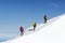 Tied climbers climbing mountain with snow field tied with a rope with ice axes and helmets