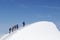 Tied climbers climbing mountain with snow field tied with a rope with ice axes and helmets