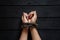 tied female hands with an old rope on a black wooden board background, tied hands