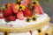 tiered layered cake with yellow wildflowers and strawberries with white icing summer cake
