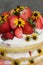 tiered layered cake with yellow wildflowers and strawberries with white icing summer cake