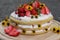 tiered layered cake with yellow wildflowers and strawberries wood board summer cake