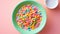 Tiffany blue bowl with colored cereal rings with milk on a pink background