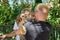 Tiger sitting on his hands bites the ear of a young man. Danger of wild animals