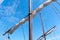 Tigging and masts of an old sailing ship against the blue sky with clouds. Travel adventure and travel concept, copy space