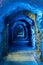 Tight and narrow old tunnel leading through a mountain with blue lighting to guide the way