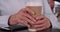 Tight shot of caucasian senior hands holding hot beverage cup outside in city