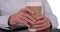 Tight shot of white senior\'s hands holding hot beverage cup on white copy space