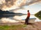 Tiired man in red shirt sit on old fishing paddle boat at mountains lake coast.