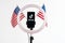 Tiktok logo on a smartphone attached to a round lamp with a tripod and two American flags on a white background. Donald Trump to