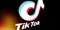 Tiktok logo on smartphone screen on black background. TikTok is a popular video-sharing social networking service owned