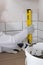 The tile installation wizard measures the correct laying of white tiles, using the yellow level, close-up