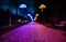 The tiled road in the night park with illuminated umbrellas. Benches in the park at night. Illumination of a park road with small