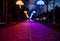 The tiled road in the night park with illuminated umbrellas. Benches in the park at night. Illumination of a park road with small