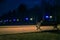 The tiled road in the night park with illuminated umbrellas. Benches in the park at night. Illumination of a park road with small