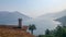 Tiled roof top and palm trees overlooking hazy mountains and lake.