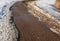 Tiled sidewalk sprinkled with sand, melting spring snow, footprints in the snow, spring background